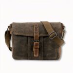 Braune Schultertasche mit Moraillonverschluss für Herren, auf hellgrauem Hintergrund