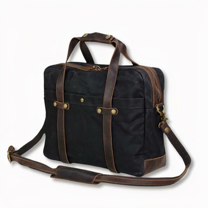 Schwarze Herren-Schultertasche mit Schulterriemen aus Wachstuch auf hellgrauem Hintergrund