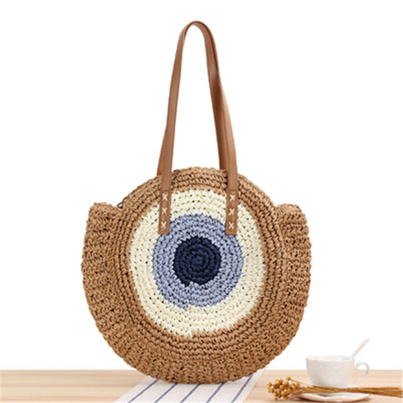 Runde Strandtasche aus gewebtem Stroh für Frauen in braun mit einem braunen Tisch als Boden
